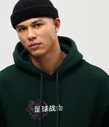 Buzo con capucha de color verde oscuro, confeccionado en tejido con felpa. Presenta un diseño estampado en la espalda con motivos de dragón y flores en color fucsia.
