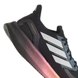 Championes de running Adidas Pureboost 5, color negro con detalles en blanco y entresuela con degradado de color que va del violeta al amarillo. Presentan parte superior de malla transpirable, cierre de cordones y suela Adiwear para mayor tracción.