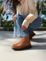 Botas cortas de cuero color marrón con elástico en los laterales y detalle de cuero texturizado en la parte delantera.