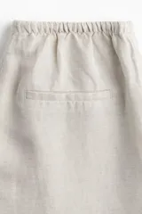 Pantalón recto color crema de tejido vaporoso en mezcla de lino. Modelo holgado con elástico y cordón de ajuste en la cintura, bolsillos laterales y traseros insertados.