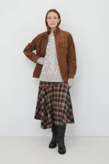 Chaqueta de gamuza en tono marrón, con cuello alto, cierre frontal con cremallera y botones a presión, y bolsillos frontales con solapa.