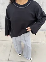 Conjunto deportivo compuesto por un buzo negro de corte cropped con costuras a la vista y un pantalón jogging gris de tiro alto, corte holgado y costuras verticales decorativas.