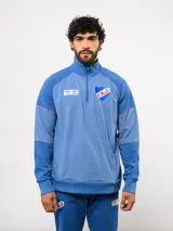 Buzo deportivo de entrenamiento con medio cierre frontal, color azul con textura jaspeada. Presenta el escudo del Club Nacional de Football y logo de Umbro en el pecho, con detalles de costuras en contraste.
