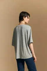 Remera de calce relajado con silueta fluida, confeccionada en tejido de viscosa con elastano. Presenta cuello redondo, mangas cortas y un diseño minimalista de caída suave.