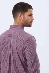 Camisa de manga larga con estampado de cuadros pequeños en tonos rojo, azul y blanco. Presenta cuello abotonado, cierre frontal con botones y un bolsillo pequeño en el pecho.