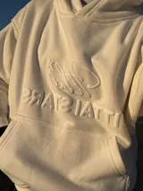 Hoodie de color blanco off-white con diseño de capucha, bolsillo frontal tipo canguro y bordado en relieve con el texto ITTAI STARS y un logo caligráfico.