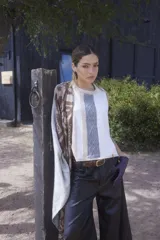 Chaleco de punto sin mangas, con diseño de bloques de color en tonos blanco, beige y gris, y detalle de trenzado vertical en el centro.