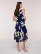 Conjunto de dos piezas en gasa azul marino con estampado floral en tonos blancos y amarillos, compuesto por un vestido midi sin mangas con forro y una capa ligera de mangas amplias.