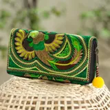 Billetera de tela bordada con diseño de ave multicolor. Tiene cierre de cremallera y tirador con pompón amarillo.
