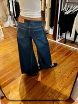 Jean de corte oxford con tiro medio-alto, confeccionado en algodón. Presenta un diseño de paneles con cortes verticales en dos tonos de azul y costuras marcadas en las piernas, ofreciendo una silueta amplia y fluida.