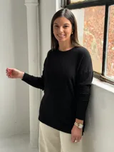 Sweater de punto color negro con diseño de rombos sutilmente integrados en el tejido, cuello redondo y mangas largas con puños ajustados.