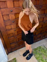 Top halter confeccionado en cuero color camel, con diseño sin mangas, espalda descubierta y ajuste mediante tiras.