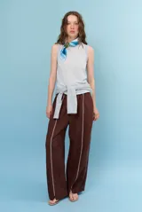 Pantalon de lino color marrón con costuras blancas decorativas a lo largo de las piernas y corte amplio.