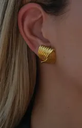 Aros dorados con diseño de líneas onduladas y forma ovalada.