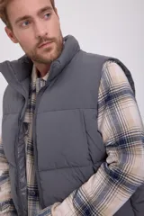 Chaleco puffer gris sin mangas con cuello alto y cierre de cremallera. Tiene bolsillos frontales y relleno de fibra sintética.