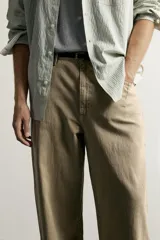 Pantalón relaxed fit de color beige, confeccionado en tejido con mezcla de algodón y lino, con diseño de cinco bolsillos, efecto lavado y cierre frontal con cremallera y botón.