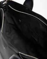 Cartera tipo tote de cuero sintético negro con doble asa de mano y correa larga ajustable. Presenta el logo de la marca impreso en plateado en el frente.