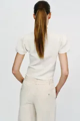 Top de punto color blanco, de cuello redondo y manga corta abullonada.