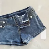 Short de denim azul tiro bajo, con diseño de doble botonadura metálica en la parte frontal y calce ajustado.