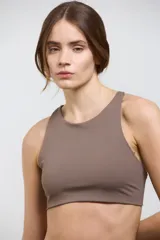 Top deportivo de compresión media con escote redondo, diseño al cuerpo y espalda abierta. Cuenta con elástico interno en la cintura para mayor sujeción.