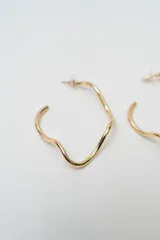 Aros tipo argolla con diseño irregular y orgánico, acabado en tono plateado.