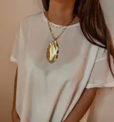 Collar dorado de doble cadena con dije irregular texturizado en tonos dorados, marrones y plateados.