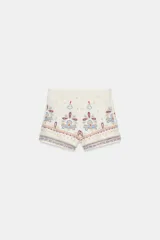 Shorts de tiro alto en color crudo con bordados decorativos en tonos azul y rojo. Presentan un diseño estructurado con cierre lateral oculto.