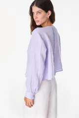 Camisa blanca de lino italiano, de manga larga, escote en V y cierre frontal con múltiples botones y detalles de alforzas.