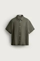 Camisa regular fit de lino color verde militar, con cuello solapa, manga corta y cierre frontal de botonadura.
