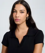 Blusa peplum negra de tejido rib, con cuello polo, escote en V y manga corta.