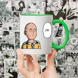 Taza blanca con interior y asa verde, estampada con la imagen de Saitama de One Punch Man y un bocadillo de diálogo con la palabra "OK".
