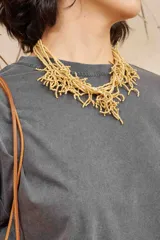 Collar de diseño orgánico inspirado en la forma del coral, confeccionado con múltiples hilos y ramas de mostacillas de color mostaza.