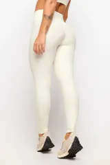 Calza larga deportiva de tiro alto en color marfil, confeccionada en tejido elástico con costuras drapeadas que realzan la figura.