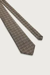 Corbata ancha de seda color marrón oscuro con estampado de raquetas de tenis y volantes. Confeccionada en tejido jacquard con forro de seda.