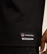 Remera deportiva negra de poliéster con tecnología Dry, cuello en V y manga corta. Estampado frontal con el número 96 y el logo de los Baltimore Ravens de la NFL.