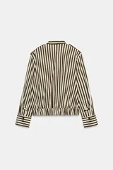 Camisa tipo bomber confeccionada en algodón, con diseño de rayas verticales en tonos marrón y blanco. Presenta cuello perkins, manga larga con puños, bolsillo de plastrón con solapa en el frente, bajo elástico y cierre frontal con botones.