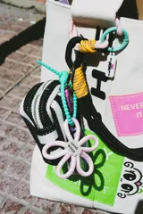 Tote bag de lona color crudo con diseño estampado que incluye parches rectangulares en colores neón y gráficos. Cuenta con doble asa superior y un amplio compartimento principal.