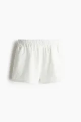 Short blanco de algodón con broderie, tiro superalto con elástico en la cintura y bolsillos laterales discretos. Presenta un corte holgado.
