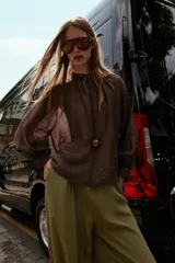 Blusa de cuello subido y manga larga abullonada con puños ajustados. Presenta un diseño semitransparente con textura arrugada y cierre frontal con botones a tono.