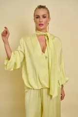 Blusa de satén color amarillo claro con escote en V y cuello de lazo ajustable. Presenta mangas largas holgadas con puños elásticos y diseño fluido.