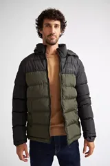 Campera puffer de nylon con diseño bicolor en negro y verde oliva. Cuenta con cierre frontal completo, capucha desmontable y logo de la marca estampado en el pecho.