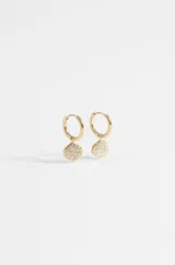 Aros de acero quirúrgico dorado tipo argolla con dije colgante en forma de moneda irregular, incrustado con strass brillante.