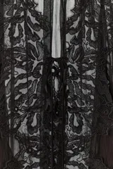 Blusa de georgette negro con mangas largas abullonadas, puños con volados y cierre frontal con lazada. Presenta una delicada aplicación de encaje floral a tono en el frente y el cuello.