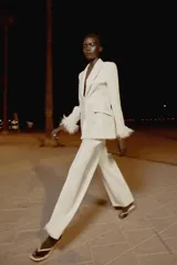 Sandalia de tacón fino medio, color blanco off-white, con diseño de tiras tipo thong para el dedo y punta cuadrada.