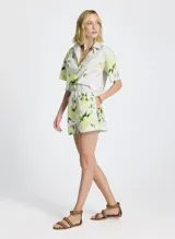 Short de tela con estampado floral en tonos blanco, verde y amarillo. Cintura elástica con cordón ajustable y puntas metálicas, bolsillos laterales y traseros.