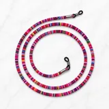 Correa para lentes de tela tejida con patrón multicolor predominando el fucsia, con terminales metálicas y sujetadores de goma negra.