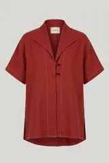 Sobrecamisa de lino color rojo ladrillo, con cuello solapa, mangas cortas y cierre frontal con dos botones. Presenta costuras a contratono en color blanco.