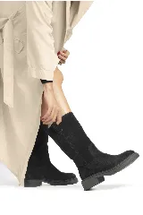 Bota de caña alta confeccionada en cuero negro, con diseño clásico y suela plana con pequeño tacón.