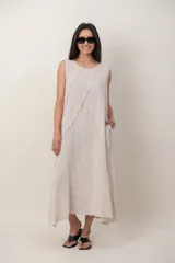 Vestido midi de lino color beige, sin mangas, con cuello redondo y diseño holgado. Presenta costuras decorativas desflecadas en la parte frontal y bolsillos laterales.