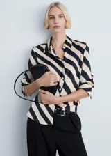 Camisa de corte recto y ajuste regular, confeccionada en tejido satinado fluido y ligero. Presenta un diseño estampado con rayas diagonales en tonos beige y negro, cuello camisero clásico, cierre frontal de botones y mangas largas con puños abotonados.